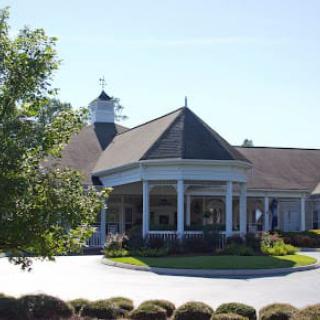 A scenic view of a building with a distinctive roof surrounded by greenery and clear skies.