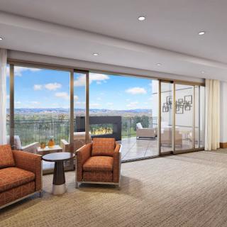 A spacious modern living room with comfortable seating, a fireplace, and large glass doors leading to a patio with scenic views.