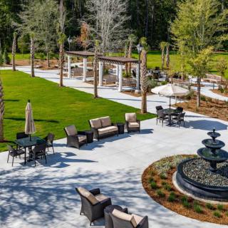 A beautifully landscaped garden featuring outdoor seating and a central fountain.