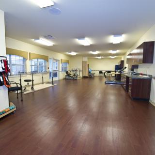 An empty fitness center with exercise equipment and wooden flooring.