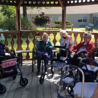 A group of seniors socializing in a gazebo on a sunny day.
