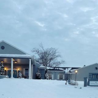 A snowy landscape featuring a house with columns and overcast skies.