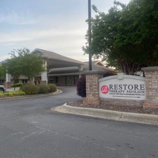 Entrance of the Restore facility showcasing its welcoming sign and well-maintained surroundings.