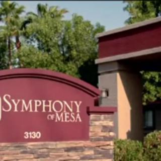 Entrance sign for Symphony of Mesa with surrounding greenery.