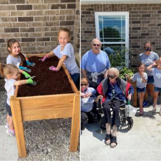 A family enjoys a sunny day working on their raised garden bed together.