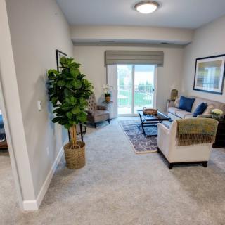 A cozy living room with modern furniture and decor, featuring a large window allowing natural light to brighten the space.
