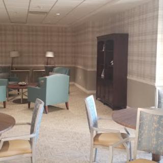 A cozy lounge area with stylish teal chairs and wooden tables.