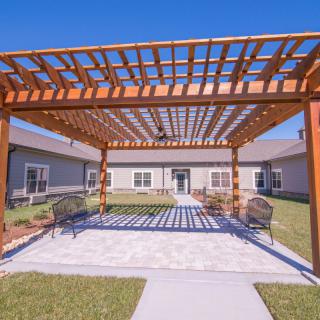 A spacious courtyard with a wooden pergola and outdoor seating on a sunny day.