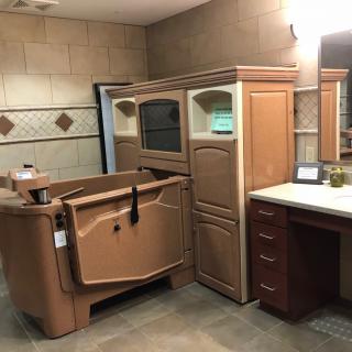 A modern bathroom featuring a walk-in tub, cabinetry, and a sink with a mirror.