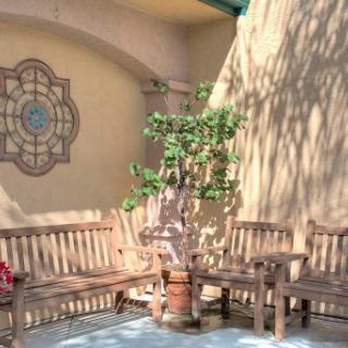 A serene outdoor space featuring wooden benches and a decorative wall, perfect for relaxation amidst nature.