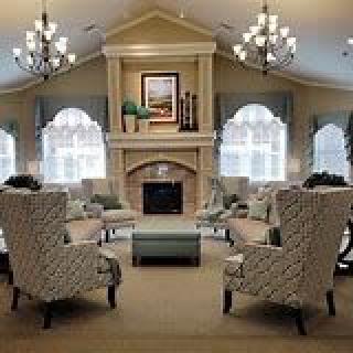 A cozy and elegant living room featuring a central fireplace, armchairs, and chandeliers.