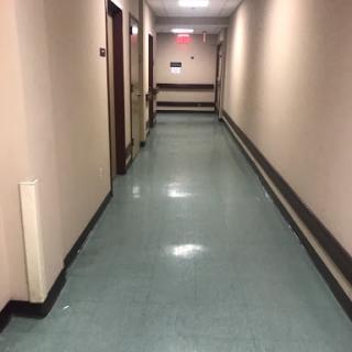 A quiet and empty hallway with a shiny floor and doors on either side.