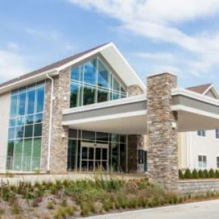 A modern building with a glass facade and stone pillars at the entrance.