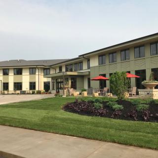 A modern two-story building with a well-maintained lawn and garden.