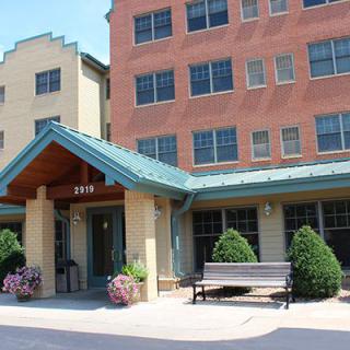 A building entrance with a bench and decorative plants outside.