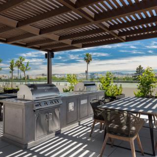 A modern outdoor kitchen under a pergola with stunning scenic views.