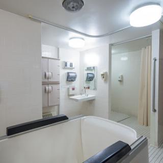 A modern and clean bathroom featuring a tub, shower, and ample lighting.
