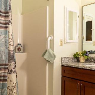 A cozy bathroom with a shower curtain, towel on a rack, and a sink with a cabinet beneath the mirror.