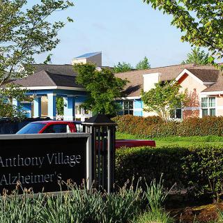 A view of a building surrounded by lush greenery, with a sign in the foreground.