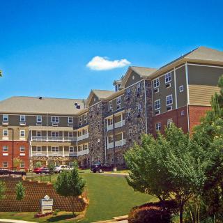 A residential apartment building surrounded by trees under a clear blue sky.