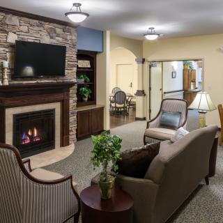 A cozy living room with a stone fireplace, comfortable seating, and warm lighting.