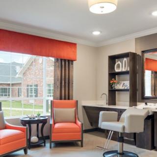 A modern living room with orange-accented chairs and ample natural light.