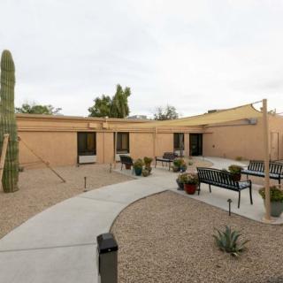 A desert courtyard with a cactus, outdoor seating, and a building in the background.