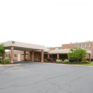 The exterior view of a hospital building with a covered entrance and surrounding greenery.