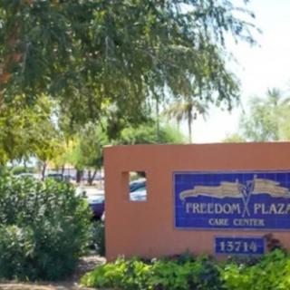 Entrance sign for Freedom Plaza surrounded by trees and greenery.