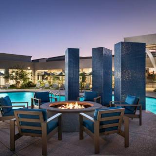 A modern outdoor seating area with a fire pit by the pool at dusk.
