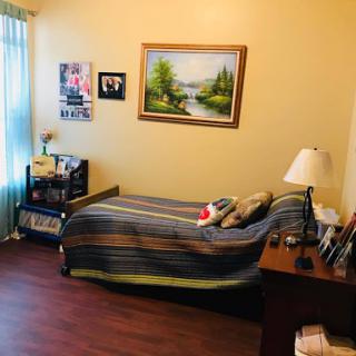 A cozy bedroom featuring a striped bedspread, a wooden desk, and decorative art on the walls.
