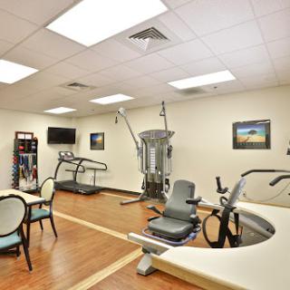 A well-equipped rehabilitation room featuring various exercise machines and a comfortable atmosphere.