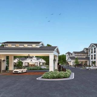 A view of a residential complex with multiple buildings and a central driveway entrance.