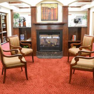 A cozy library setting with armchairs arranged around a fireplace.