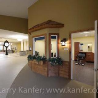 A spacious hallway with a clock and an open door leading into a room.