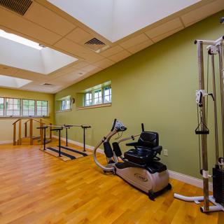 A compact exercise room equipped with fitness and rehabilitation machines.