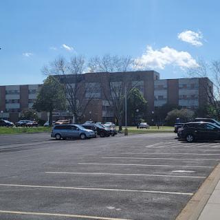 A sunny day with a view of a parking lot and a nearby building.