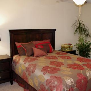 A cozy bedroom with a floral bedspread and warm lighting.
