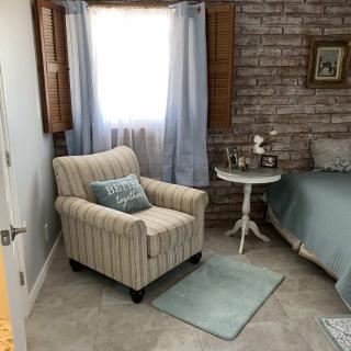 A cozy bedroom corner featuring an armchair, side table, and brick wall.