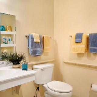 A neatly organized bathroom with a toilet, sink, and colorful towels.