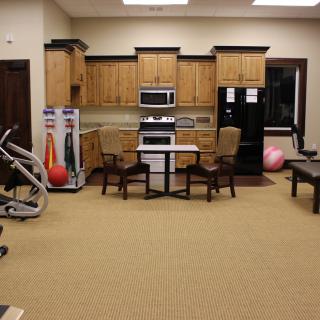 A multi-purpose room featuring kitchen appliances and rehabilitation exercise equipment.