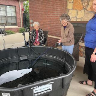 Seniors enjoying an outdoor activity by a large water container.