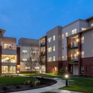 A modern apartment complex with illuminated windows and a courtyard at night.