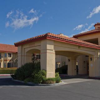 An exterior view of a hotel entrance with a clear sky overhead.
