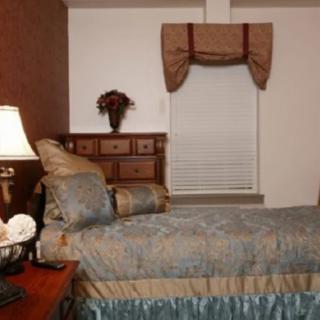 A neatly arranged bedroom featuring a bed, dresser, and lamp.