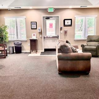 A cozy waiting room with comfortable seating, large windows, and soft lighting.
