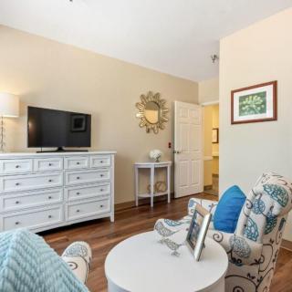 A cozy living room with a dresser, television, and stylish seating area.
