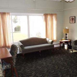 A cozy living room with a sofa, side table, and large windows with curtains.