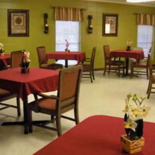 A cozy dining area with tables covered in red tablecloths and elegant decor.