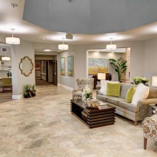 A spacious and elegantly designed living room featuring modern furniture, decorative plants, and wall art.